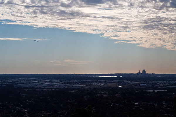 a distant plane over a distant Perth city